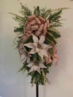 a bouquet of flowers sitting on top of a black stand next to a white wall