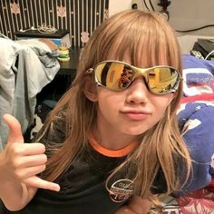 a girl wearing sunglasses giving the thumbs up