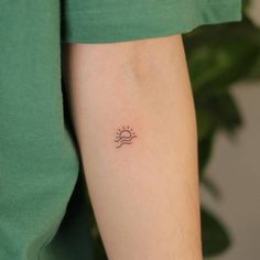 a woman's arm with a small sun tattoo on the left side of her arm