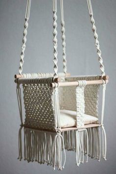 a hanging chair made out of macrame beads and tassels, with a cushion in the middle