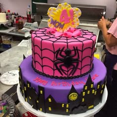 a spiderman birthday cake is decorated with pink and purple icing