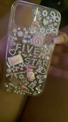 someone is holding up their phone case with jewels and candies all over the back