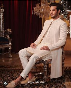 a man sitting on top of a chair wearing a white suit