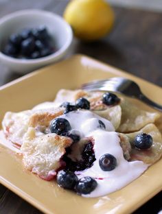 a plate topped with blueberries and crepes covered in cream