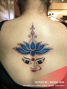 the back of a woman's shoulder with a tattoo design on her left side