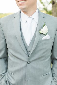 a man in a gray suit and white flower