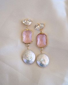 Add a touch of elegance and feminine flair to your wedding day look with our stunning Arabella Pink Drop Gold Earrings. These beautiful gold and pink drop earrings feature eye-catching freshwater coin pearls, making them a perfect choice for the boho bride who wants a pop of color to her wedding look or bridesmaid outfits! ----------------------  EARRINGS FEATURE ◊ Material: Flat Freshwater Pearls, Cubic Zirconia, Brass, Glass ◊ Dimensions/Size: 2" drop ◊ Finish: 18k Gold Plating ◊ Freshwater pearls are hand wire-wrapped with 14K gold fill wire ----------------------  PACKAGING ◊ We do the gift-wrapping for you! All jewelry comes packaged in our custom, foiled pressed gift boxes.  ---------------------- FREE US STANDARD SHIPPING on orders of $35 or more! No code required ------------------ Feminine Drop Earrings For Bridal Party, Feminine Dangle Bridal Earrings For Party, Elegant Pink Chandelier Earrings For Formal Occasions, Elegant Pink Chandelier Earrings For Formal Events, Elegant Pink Teardrop Pearl Earrings, Feminine Bridal Drop Earrings As Gift, Elegant Pink Bridal Earrings, Feminine Bridal Drop Earrings For Gifts, Pink Feminine Pearl Earrings For Wedding