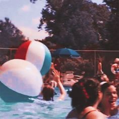 some people are playing in the water and having fun with their balloons while others watch