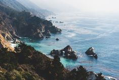 the ocean is surrounded by rocky cliffs and trees