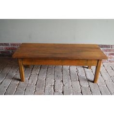 a wooden coffee table sitting on top of a brick floor in front of a wall