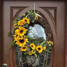 a wreath with sunflowers and greenery hangs on the front door's glass