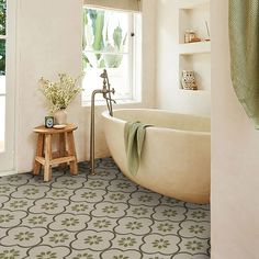 a bath tub sitting next to a window in a bathroom under a green towel on a rack