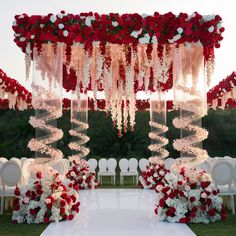 an outdoor wedding setup with red and white flowers on the aisle, draped in clear acrylic