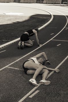 two women laying on the side of a race track