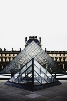 the glass pyramid is in front of an old building