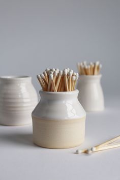 three white vases with tooth brushes in them