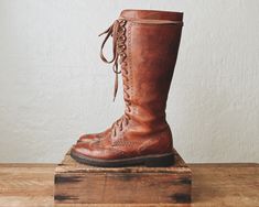 ꞊ Extraordinarily rare Cole Haan 1930's style knee high lace up boots in warm whiskey brown. ꞊ Thick solid leather, beautifully made. ꞊ Wingtip detailing. ꞊ brass grommets and textured sole. ꞊ Condition is good with minor creasing, a few scuffs/scratches on the toe and shaft, grommet patina, and some slight discoloration to laces from the grommets. I might replace the laces with waxed cord to make them easier to lace/unlace but the ones they have work fine. ||   M E A S U R E M E N T S   || Labeled As: 8B Fits Like: true to size with thin socks Ball: 4" sole: 10.75" Heel: 1.25" Total Height: 15" Knee High Lace Up Boots, Lace Up Knee High Boots, 1930's Style, 1940's Style, 40s Fashion, 1930s Fashion, 1940s Fashion, Work Boots, Boot Shoes Women