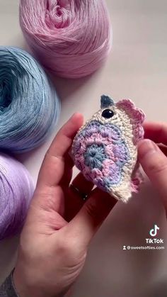 someone is holding a small crocheted bird in their hand next to some yarn