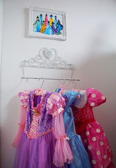 three dresses hanging on a rack in front of a wall with a picture above it