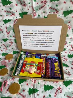 an open box filled with candy sitting on top of a bed covered in christmas decorations