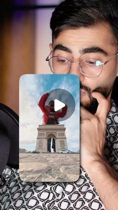 a man holding up a card with the image of a person standing in front of a monument