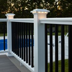 a black and white fence with lights on it next to a swimming pool in the evening