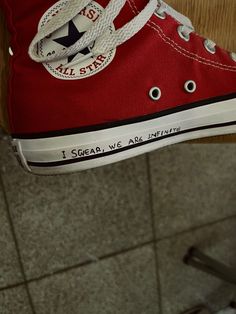 a person's red converse sneakers with writing on the bottom and white laces