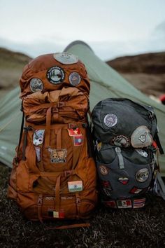 two backpacks sitting next to each other in front of a tent