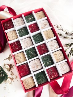 a red box filled with assorted chocolates next to a pink ribbon and christmas decorations