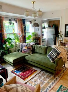 a living room filled with furniture and lots of plants in the window sills