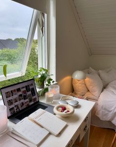 a laptop computer sitting on top of a white desk next to a lamp and window