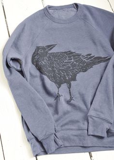 This super soft sweatshirt is hand printed with our original Crow design in our Rockport, Maine studio. Spun from plush sponge fleece fabric, this remarkably soft unisex pullover crewneck sweatshirt lends itself to daily wear and year-round layering. Featuring ribbed cuffs and waistband, a crew neck, and fashion-forward fleece fabrication. Details: * Original Hearth and Harrow Crow design, printed in black * Bella + Canvas Sponge Fleece Raglan Sweatshirt in heathered navy * Eco-friendly, water-b Crow Design, Rockport Maine, Raglan Sweatshirt, Sweatshirt Crewneck, Bird Print, Wren, Print Pullover, Bird Prints, Fleece Fabric