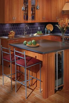 a kitchen with wooden cabinets and red chairs