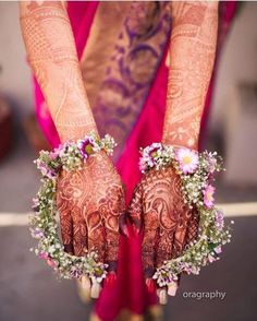 two hands with henna decorated with flowers and greenery on their palms are shown