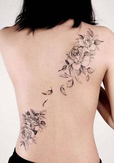 a woman's back with flowers and birds tattoo on her left side ribcage