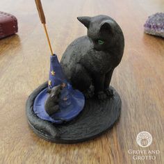 a cat figurine sitting on top of a witches hat with a mouse in it