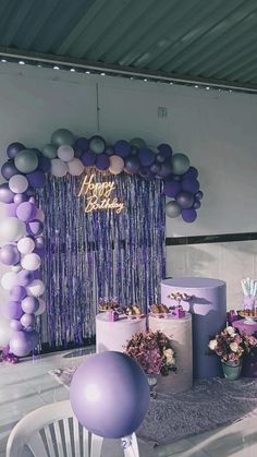 purple and white balloons are hanging over the table