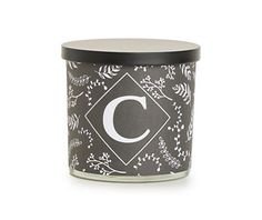 a candle with the letter c on it and floral designs in black, white and grey