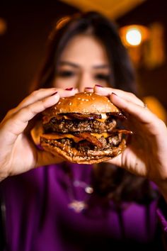 a woman holding up a hamburger in front of her face