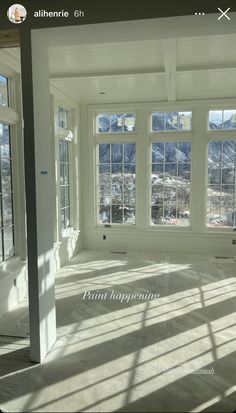 an empty room with large windows and mountains in the background