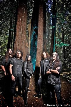 three men standing in front of trees with their arms crossed and looking at the camera