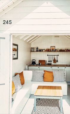 a white couch sitting under a window next to a wooden table