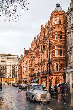 cars are parked on the street in front of old buildings and people with umbrellas