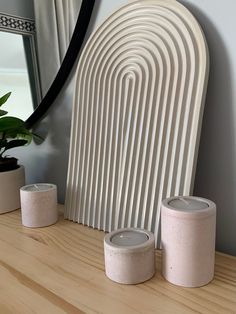 three candles sitting on top of a wooden table next to a mirror and potted plant