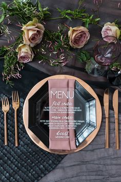 a table setting with pink roses and silverware on it, along with menus