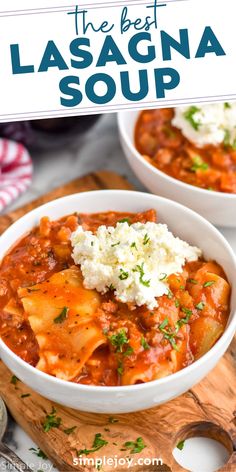 two white bowls filled with lasagna soup on top of a wooden cutting board