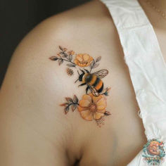 a woman with a bee and flowers tattoo on her back shoulder, showing it's chest