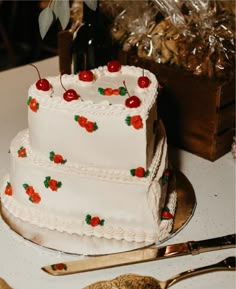 a three tiered cake with cherries on it and two wine bottles in the background