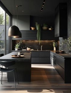 a modern kitchen with black cabinets and wood flooring is pictured in this image, there are two hanging lights above the island