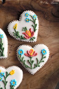 three decorated heart shaped cookies sitting on top of a wooden table